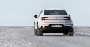 Rear view of a white Polestar 2 on a gravel road, showcasing sleek taillights and wheels.