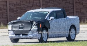 Camouflaged Ford electric truck, front angle, visible wheels, and covered charging port.