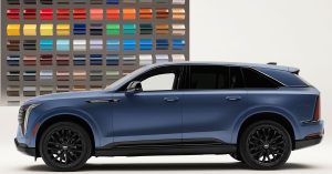 Side view of a blue Cadillac Escalade IQ with black wheels, showroom setting, color samples in background.