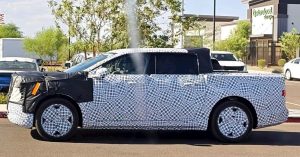 Side view of a camouflaged electric pickup with covered front and rear features.