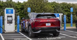Red electric vehicle parked at charging station, showcasing rear design and charging port.
