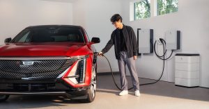 Red electric vehicle charging in a garage, with a person connecting the charger.
