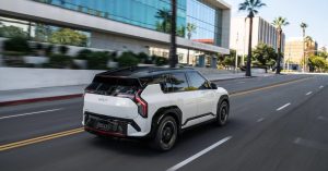 Kia EV3 driving on a road, showcasing a white exterior and black roof.