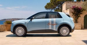 Side view of a light blue car with unique wheels, parked in a scenic outdoor setting.