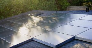 The image shows solar panels installed on a sloped roof, reflecting sunlight.