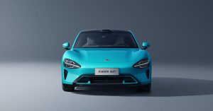 Front view of the Xiaomi SU7, featuring a turquoise color, sleek headlights, and a smooth design.