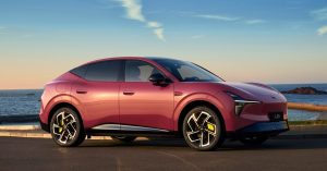 Side view of Xpeng Mona L05, featuring sleek design, alloy wheels, and coastal background.