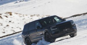 Black Zeekr 9X SUV driving on snow, showcasing front grille and sporty wheels.