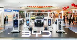 BYD vehicles displayed in a mall showroom with charging stations and promotional signage.