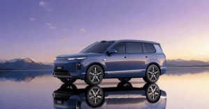 Blue electric vehicle parked by a reflective surface, showcasing sleek design and alloy wheels.