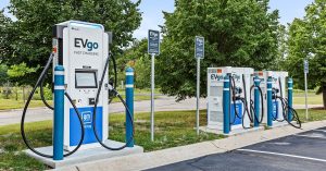 Four EVgo fast charging stations in a parking lot, surrounded by trees.