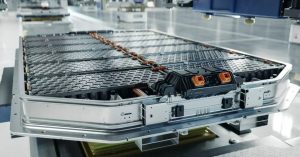 Image shows a solid-state battery pack in a factory setting, featuring multiple battery cells and connectors.