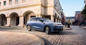Blue SUV parked on a cobblestone street, showcasing a sleek front design and alloy wheels.