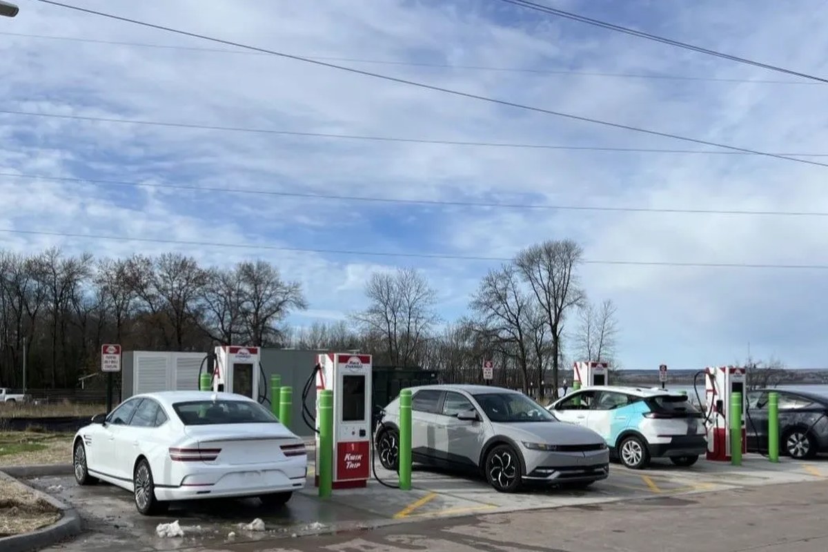 Three electric vehicles parked at fast-charging stations in an outdoor setting.