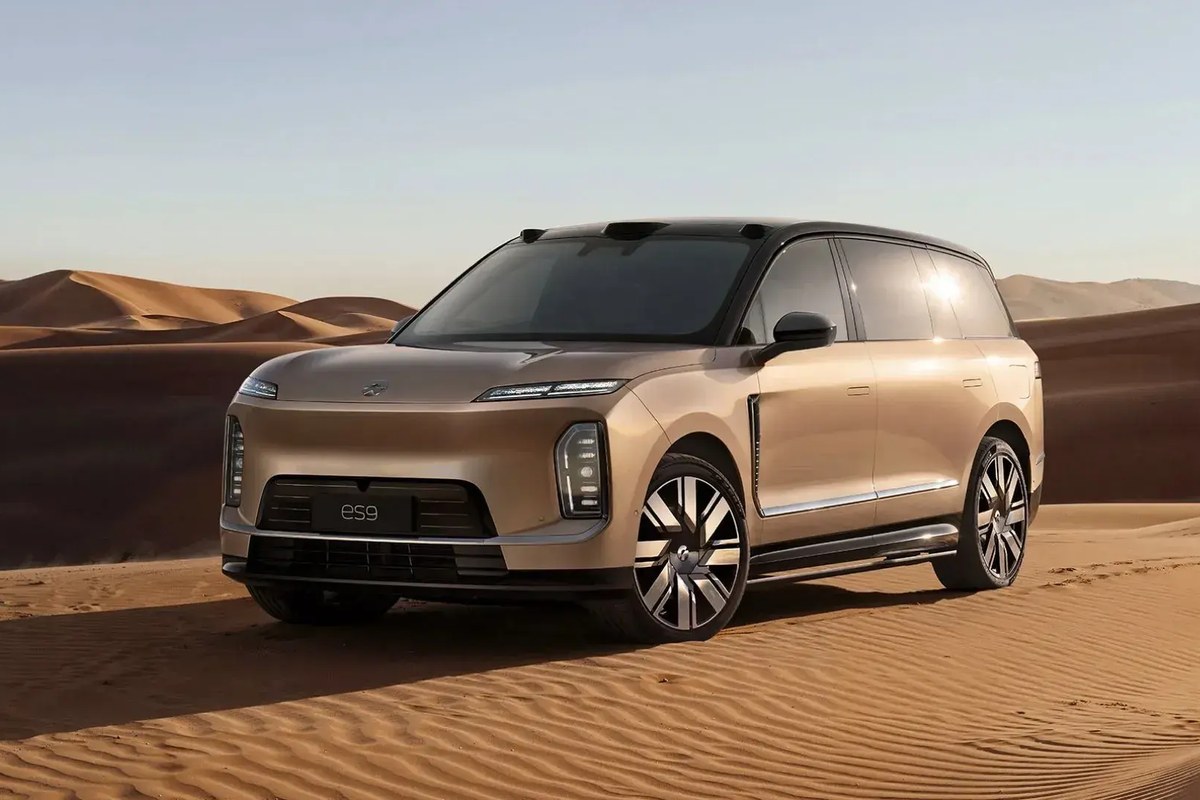 Nio ES9 parked on sand dunes, showcasing a sleek front design and large wheels.