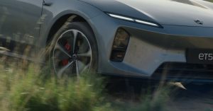 The image shows a close-up of the front wheel, featuring red brake calipers and sleek alloy design.