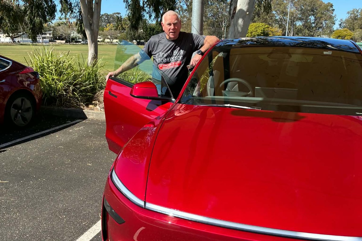 Red Tesla Model Y parked, showing open driver's door and interior with light seats.