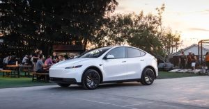 White Tesla Model Y parked at an outdoor event, showcasing sleek design and black wheels.