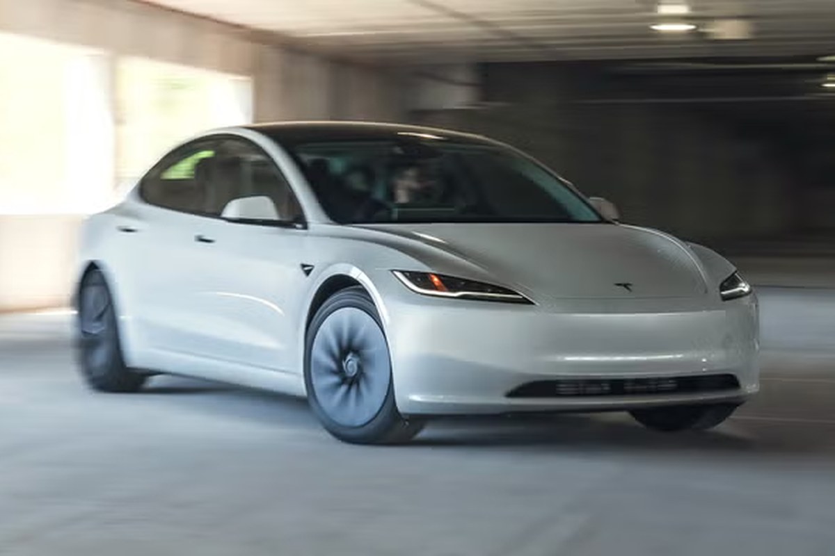 White Tesla EV in motion, showing front angle, sleek design, and dark wheels.