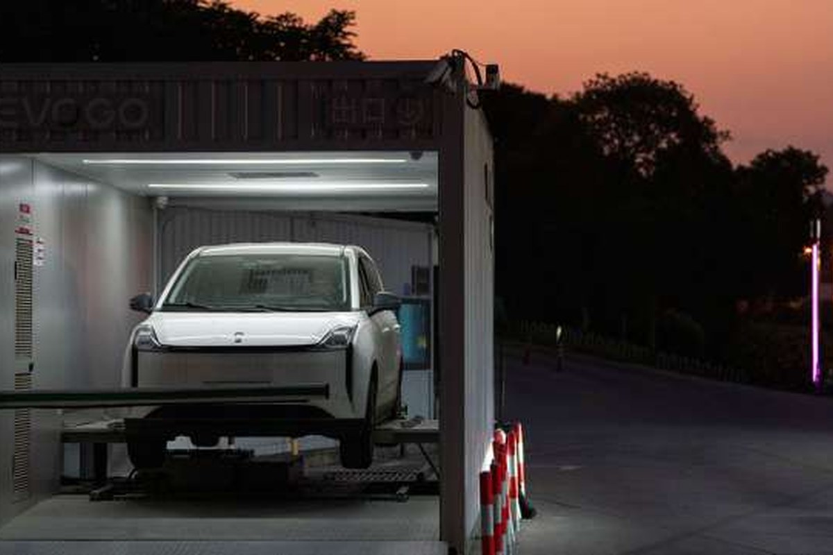 The vehicle is positioned in a battery-swapping station, illuminated at night.