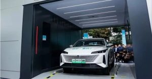 The vehicle is positioned at a slight angle in a battery-swapping station, showcasing its front design and sleek lines.