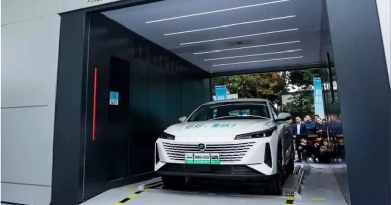 The vehicle is positioned at a slight angle in a battery-swapping station, showcasing its front design and sleek lines.