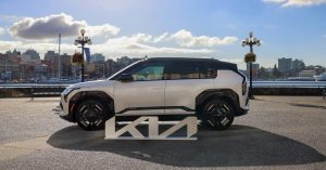 Side view of Kia EV3 with black wheels, sleek design, and waterfront setting.