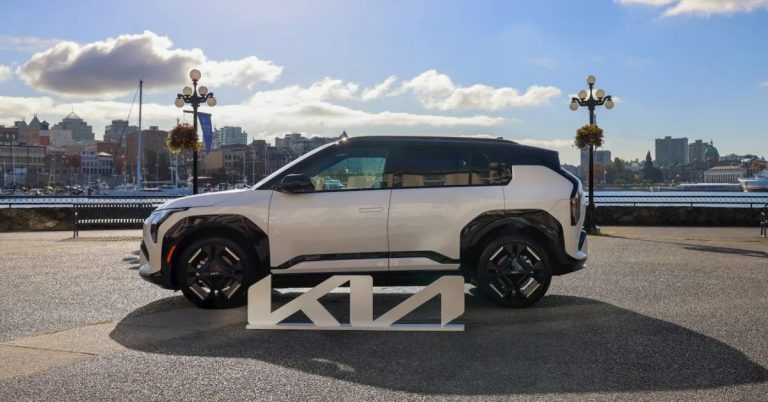 Side view of Kia EV3 with black wheels, sleek design, and waterfront setting.
