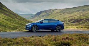 Kia EV6 GT in blue, side view, showcasing sporty wheels and sleek design in a scenic landscape.