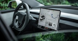 Interior view featuring a large touchscreen displaying navigation, steering wheel, and dashboard.