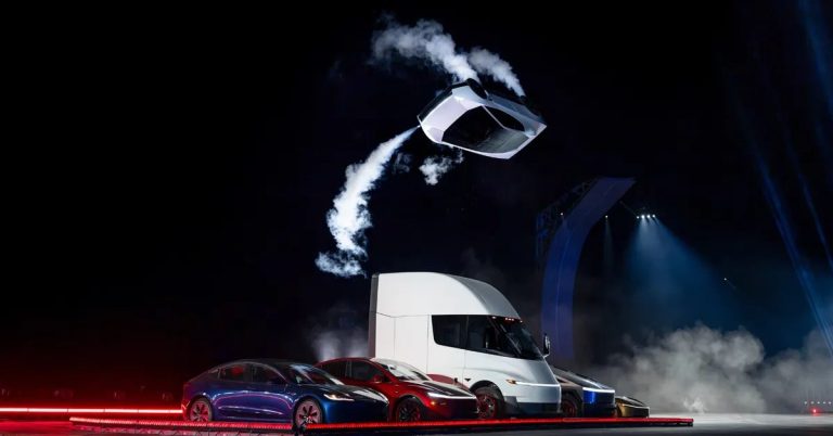A Tesla vehicle is airborne, with a semi-truck and two cars below in a dark setting.