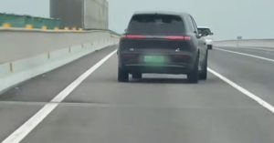 Rear view of a black Voyah Taishan on a highway, showing sleek taillights and license plate.